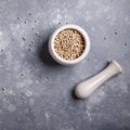 White peppercorns in a mortar for spices. Stone mortar and pestle full white pepper on gray background. Top view. Copy space