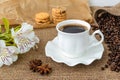 White peruvian lily flower, hot coffee in white elegant cup with saucer, sweet cookies and scattering of coffee beans on rustic Royalty Free Stock Photo