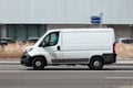 White Peugeot Boxer panel van in fast motion on city street. Fast moving cargo car on urban road