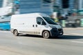 White Peugeot Boxer panel van in fast motion on city street. Fast moving cargo car on urban road