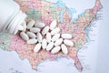 White pharmaceutical pills spilling from prescription bottle over map of America background Royalty Free Stock Photo