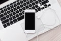 white phone with a black screen and headphones lies on the laptop keyboard Royalty Free Stock Photo