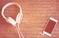 White phone and headphones flat lay on wooden table. Warm orange light toned photo. Royalty Free Stock Photo