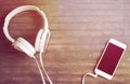 White phone and headphones on wooden table. Warm yellow toned photo.