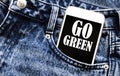 White phone with text Go Green lies in jeans pocket