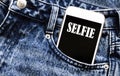 White phone with text selfie lies in jeans pocket