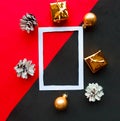 White photo frame and golden Christmas decorations on geometric red and black abckground. Flat lay, top view, copy space. Royalty Free Stock Photo