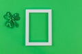 White photo frame and sharmrock on green paper background