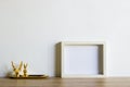 A white photo frame with mini golden animal heads over the wooden table.