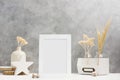 White Photo frame mock up with plants in vase with wooden and ceramic home decor on shelf. Scandinavian style Royalty Free Stock Photo