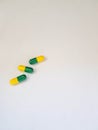  white photo of three medicine capsules green and yellow