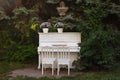 White piano and chairs with romantic decor in summer in garden. Decor for a wedding or a romantic dinner. Grand piano decorated wi