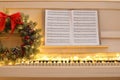 White piano with fairy lights, beautiful Christmas wreath and music sheets, closeup Royalty Free Stock Photo