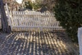 White picket fence casting long shadows on the edge of a cemetary