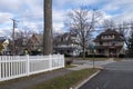 White picket fence street and sidewalk of suburban homes with leafless late fall winter season trees Royalty Free Stock Photo