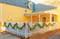 white picket fence strung with green garland and red bows for Christmas on street corner Royalty Free Stock Photo