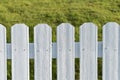 White picket suburban fence with green grass.