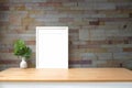 White picture frame and houseplant on wooden table with brick wall Royalty Free Stock Photo