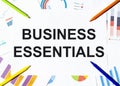 White piece of paper with text Business Essentials on the background of the graphs, multi-colored felt-tip pens