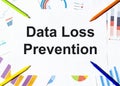 White piece of paper with text Data Loss Prevention on the background of the graphs, multi-colored felt-tip pens Royalty Free Stock Photo