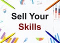 White piece of paper with text Sell Your Skills on the background of the graphs, multi-colored felt-tip pens