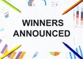 White piece of paper with text Winners Announced on the background of the graphs, multi-colored felt-tip pens Royalty Free Stock Photo