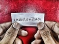 On a white piece of paper the word unrelenting written in hands with beautiful shinny background Royalty Free Stock Photo