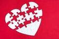 White pieces jigsaw combine lovely heart shape on red background using as jigsaw of love, family, broken heart or Valentines day Royalty Free Stock Photo