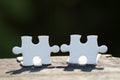 2 white pieces of puzzle stand on wooden table isolated on black background, concept of connecting