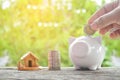 Hand holding coin with white piggy bank and home on old wood tree bokeh background.concept save money Royalty Free Stock Photo