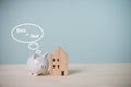 White piggy bank with text Rent or Sale and mini wood house model on an old wooden table. Income from Investment property for a Royalty Free Stock Photo