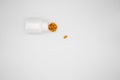 White pill bottle and orange pills in a lid on a white background Royalty Free Stock Photo