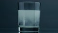 White pill dissolving glass at dark background closeup. Effervescent tablet flow