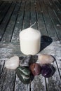 White Pillar candle with small collection of crystal tumbled gem stones Royalty Free Stock Photo
