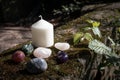 White Pillar candle with small collection of crystal tumbled gem stones in rustic setting Royalty Free Stock Photo