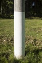 White pillar. Painted pole in park. Technical object