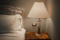 White pillow on bed and lamp on bedside table Royalty Free Stock Photo