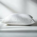 A white pillow with a soft texture rests on a smooth white surface, casting slight Royalty Free Stock Photo