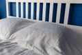 With white pillows and white linens on the white large wooden double bed in the bedroom against the blue wall. White pillows on th Royalty Free Stock Photo