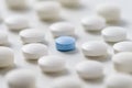 White pills with ablue one in the middle on white backgroung Royalty Free Stock Photo
