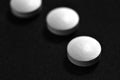 White pills on black background