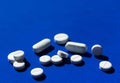 White pills on a blue background. Close-up. Copy space. Royalty Free Stock Photo