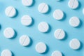 White pills on blue background pattern. Chaotically scattered round white pills, medical concept. Flat lay, minimalist design, top Royalty Free Stock Photo