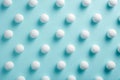 White pills on blue background pattern. Chaotically scattered round white pills, medical concept. Flat lay, minimalist design, top Royalty Free Stock Photo