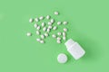 White pills and bottle on green background. Medical pharmacy concept. Probiotics benefits. Royalty Free Stock Photo