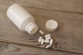 White pills with bottle on wooden table Royalty Free Stock Photo