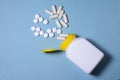 White pills and capsules poured from a plastic medical jar on a blue background Royalty Free Stock Photo