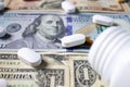 White pills and a medical bottle on one and one hundred dollar bills. Health insurance concept. Medicine and money.