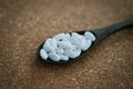White pills and medicines in the wooden spoon on a brown cork background. Royalty Free Stock Photo