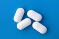 Four white oblong tablets lie on a blue background. Royalty Free Stock Photo